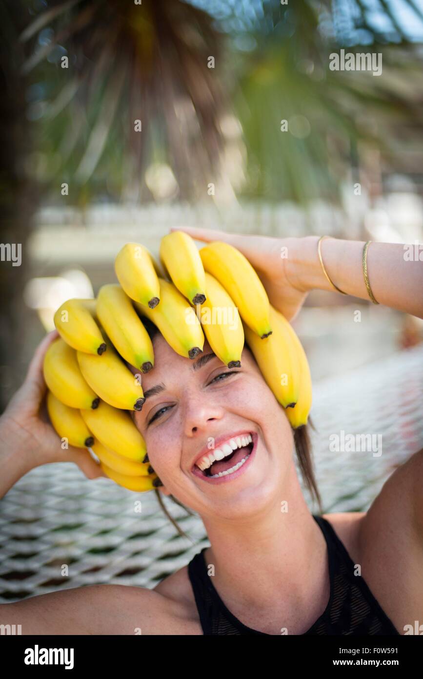 Portrait of young woman at beach with bananas on head, Islamorada, Florida, USA Stock Photo