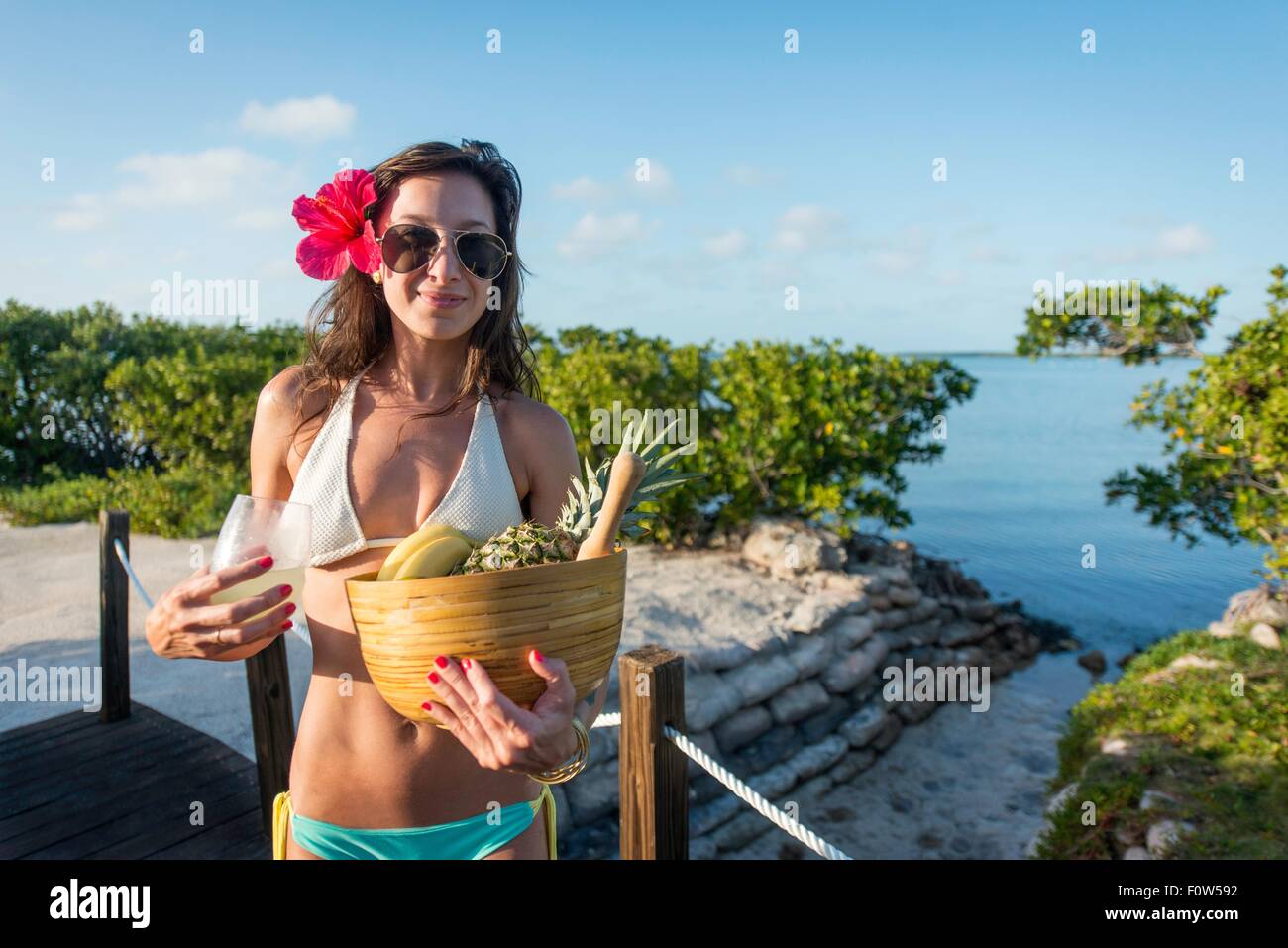 Portrait of young woman at beach carrying bowl of fruit, Islamorada, Florida, USA Stock Photo