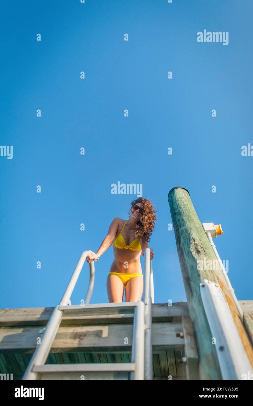 Low angle view of young woman on sea pier Stock Photo