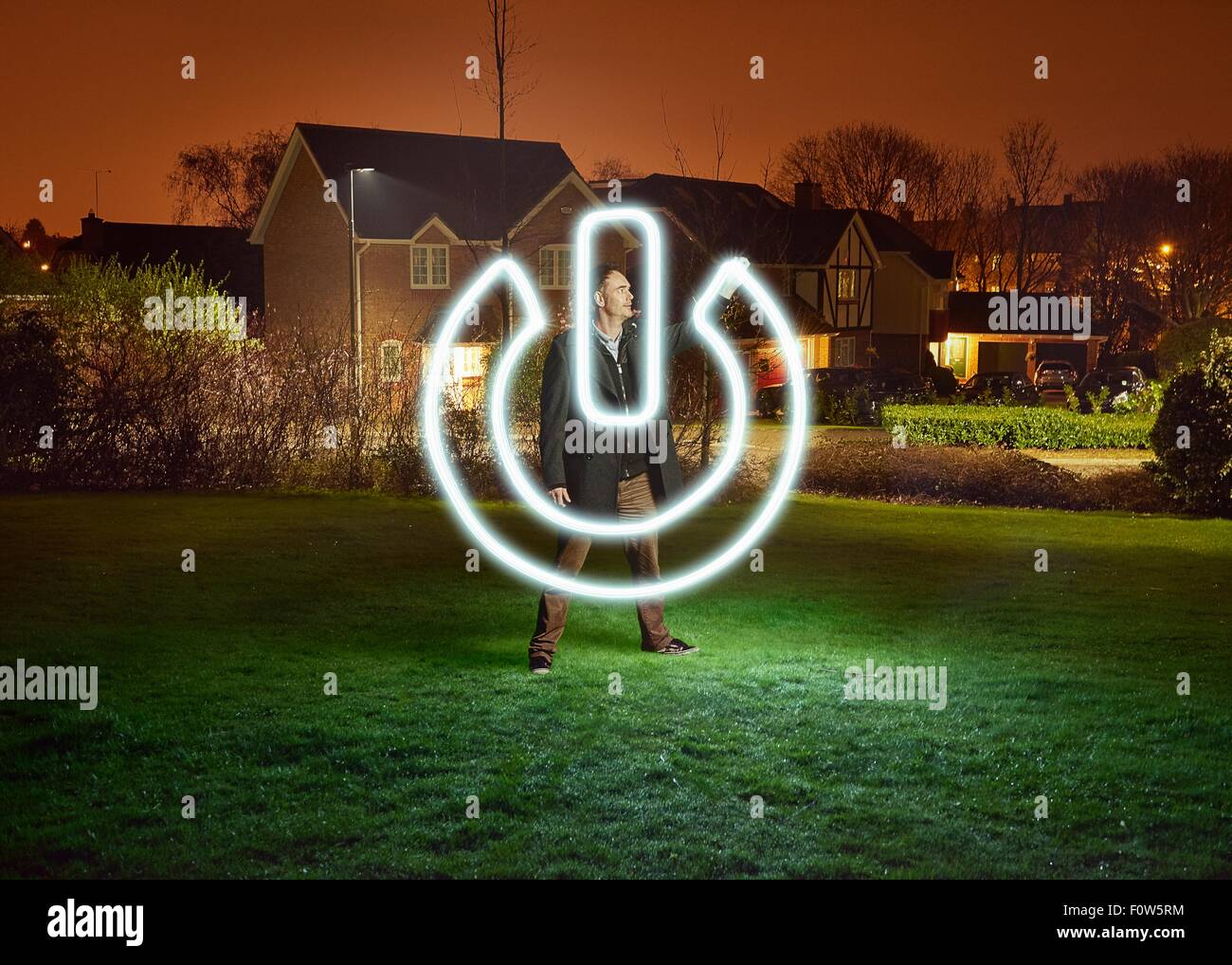 Artist light painting a power switch symbol in park Stock Photo
