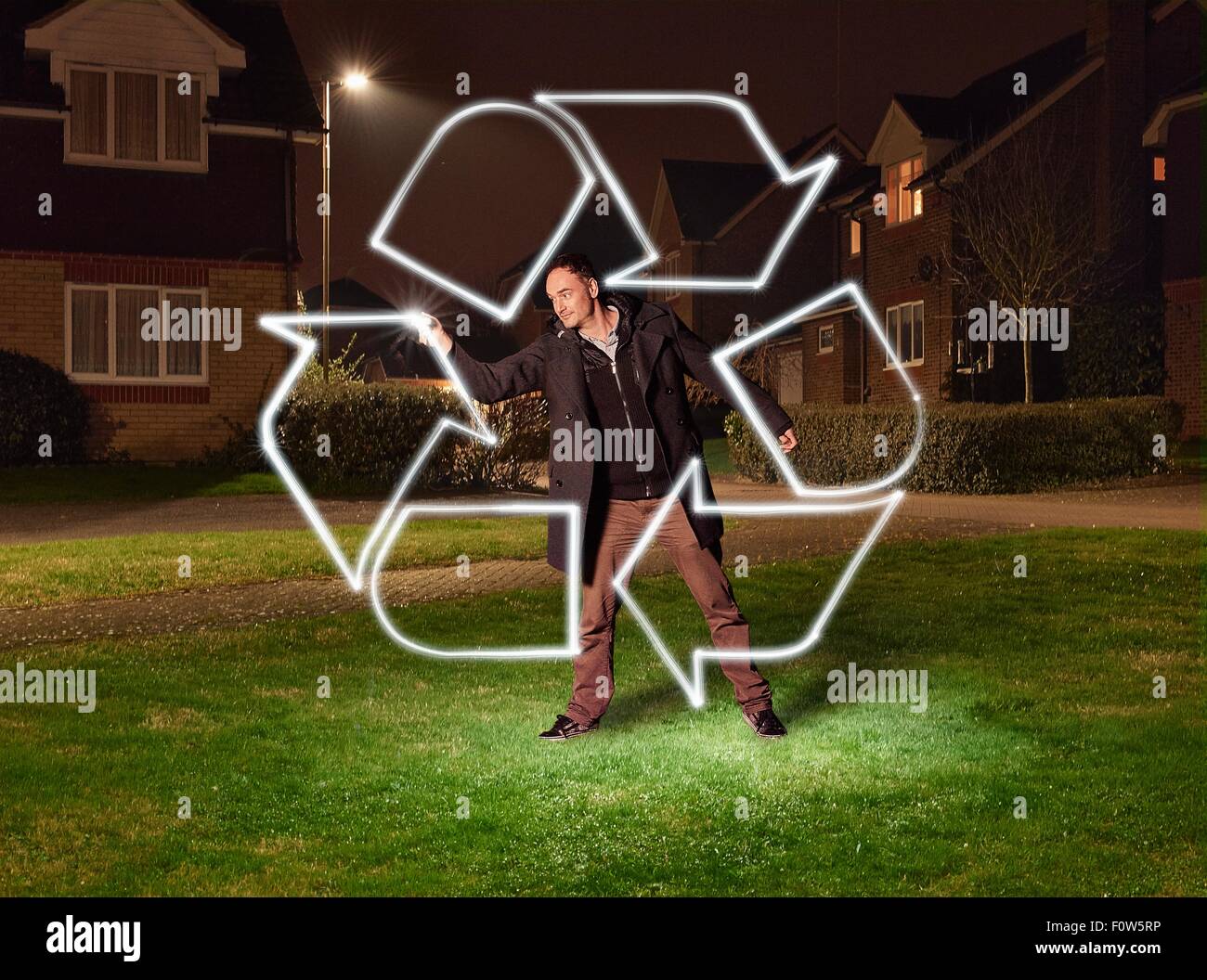 Artist light painting a recycling symbol in park Stock Photo