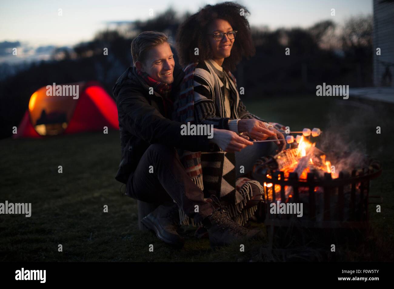 Couple toasting marshmallows at camp, Isle of Skye, Scotland Stock Photo