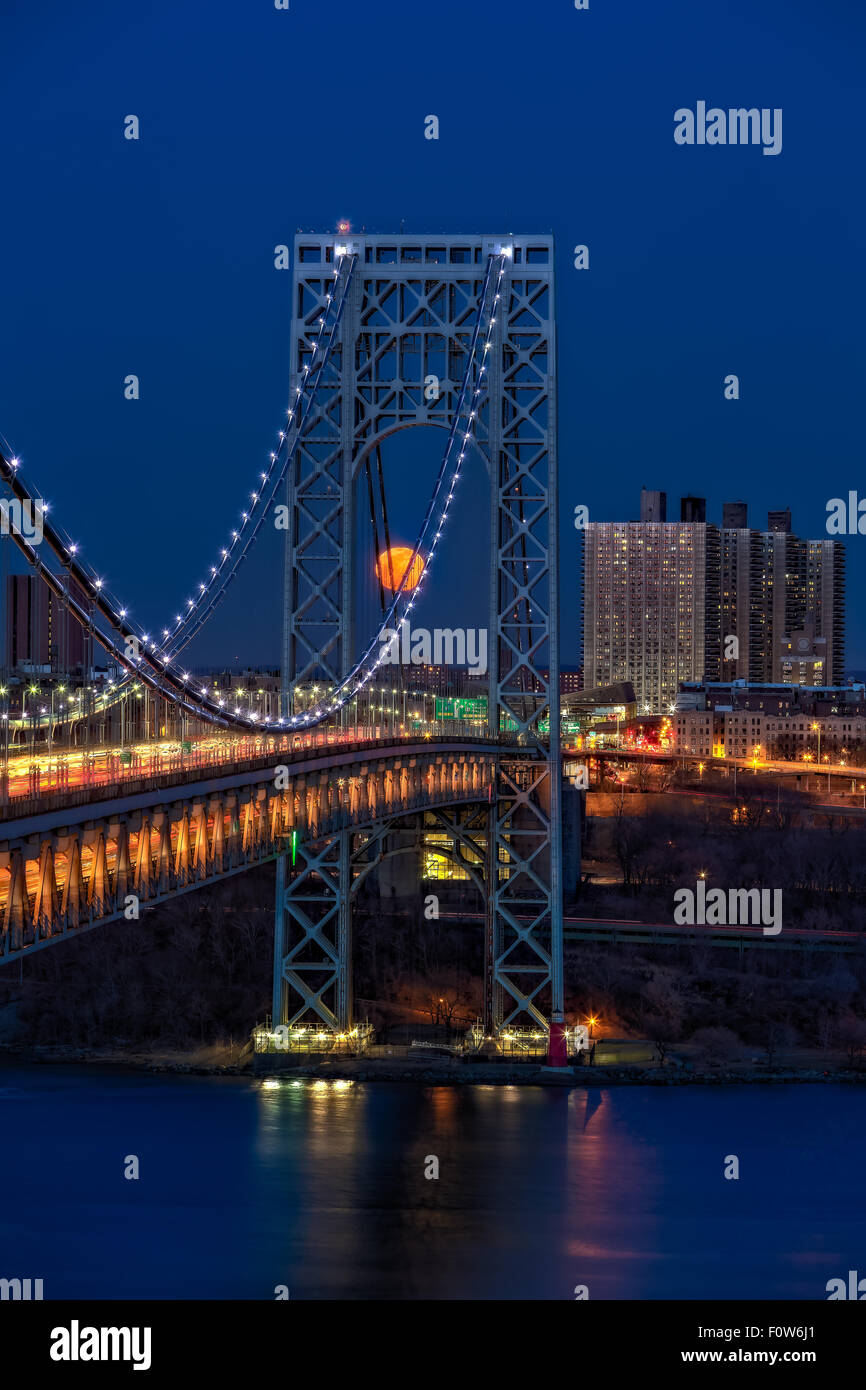 George Washington Bridge Full Moonrise - The full moon rises by the illuminated George Washington Bridge (GWB) and Jeffrey's Hook Lighthouse, also know as the big gray bridge and the little red lighthouse. This moonrise occurred on the evening of a blood moon due to a total eclipse of the moon earlier in the morning. The eclipse was one of the shortest total eclipses to occur in years, lasting only four and half minutes. Stock Photo