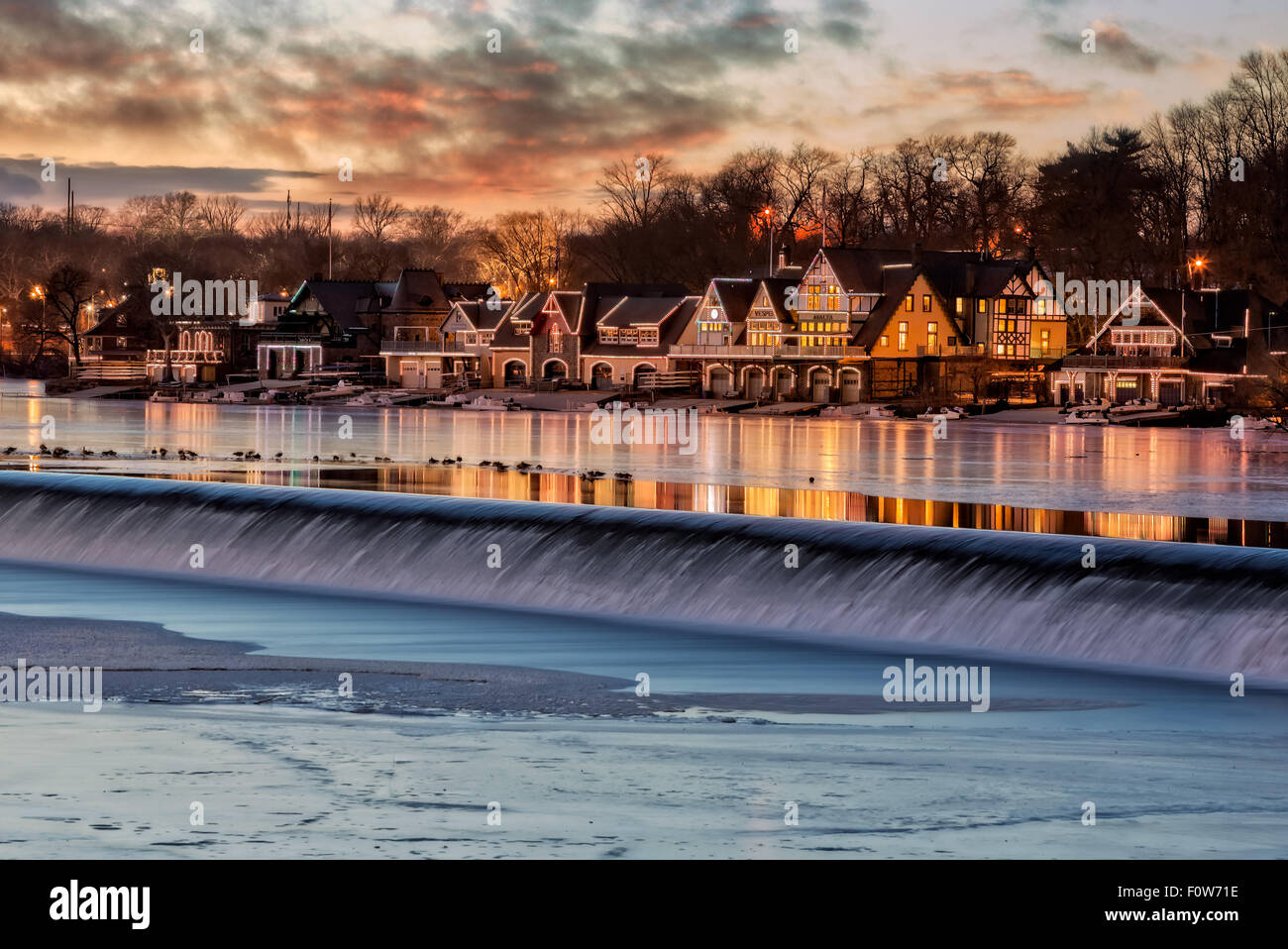 Boathouse Row Philadelphia, Pennsylvania - Computerized LED lights turn on to illuminate and outline each of the houses at Boathouse Row. The colorful lights are reflected on the frozen waters of the east bank of the Schuylkill River as is the colors of the setting sun and sky. Seen in the foreground is the Fairmount Water Works on the Schuylkill river dam. Boathouse Row hosts several major rowing regattas, it  is a National Historic Landmark and was listed on the National Register of Historic Places in 1987. Stock Photo