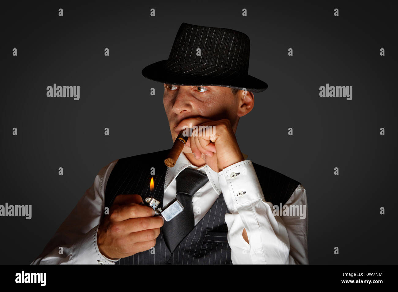 young gangster with hat smoking cigar, studio shot Stock Photo