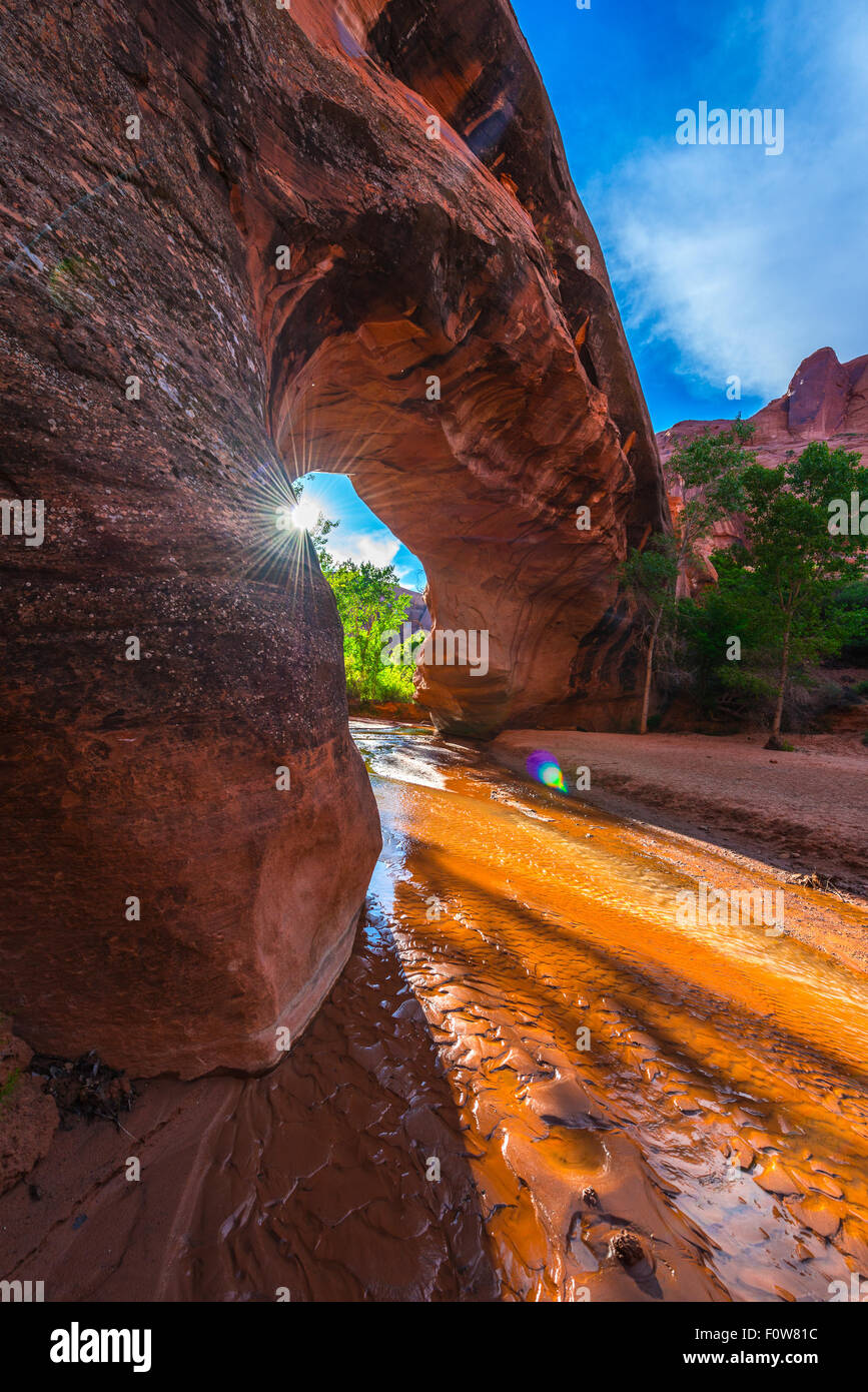 Sun Peeking from behind the Beautiful Natural Arch in Coyote Gulch Escalante National Stock Photo