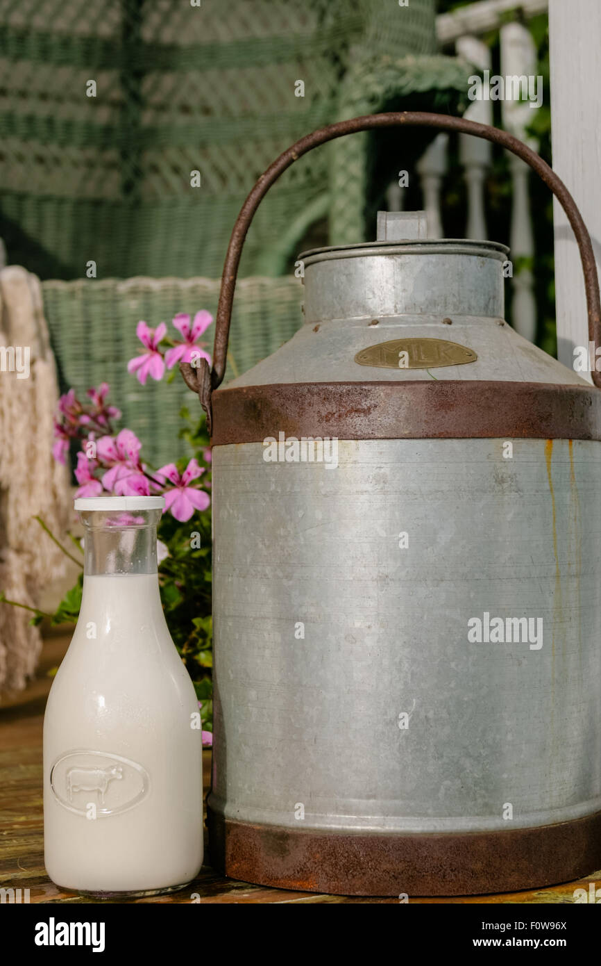 Old fashioned milk can and bottle at the steps of a country house porch. Stock Photo