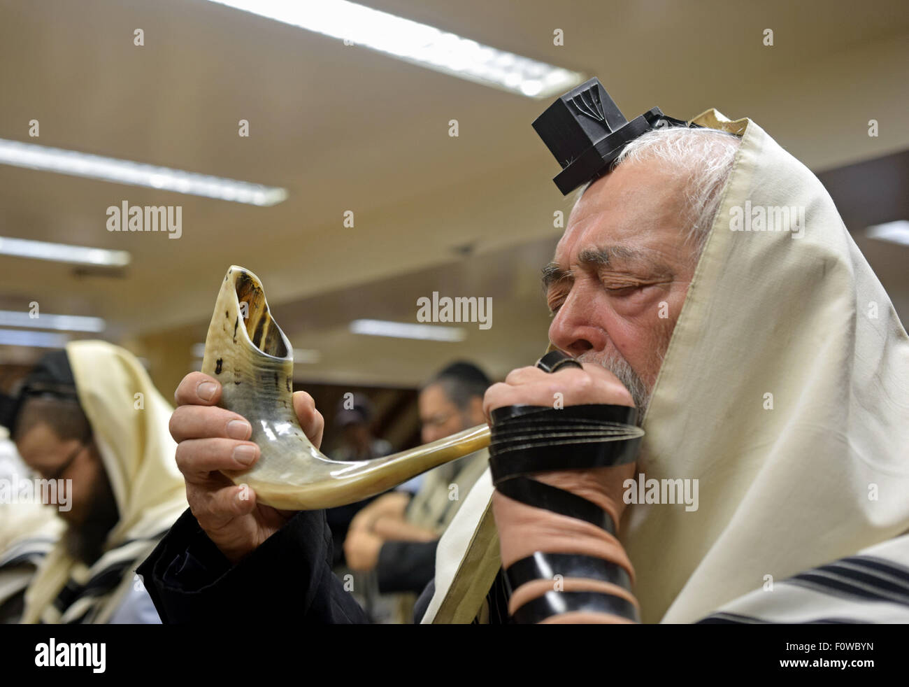 A very religious Jewish man blowing a shofar ram's horn at morning