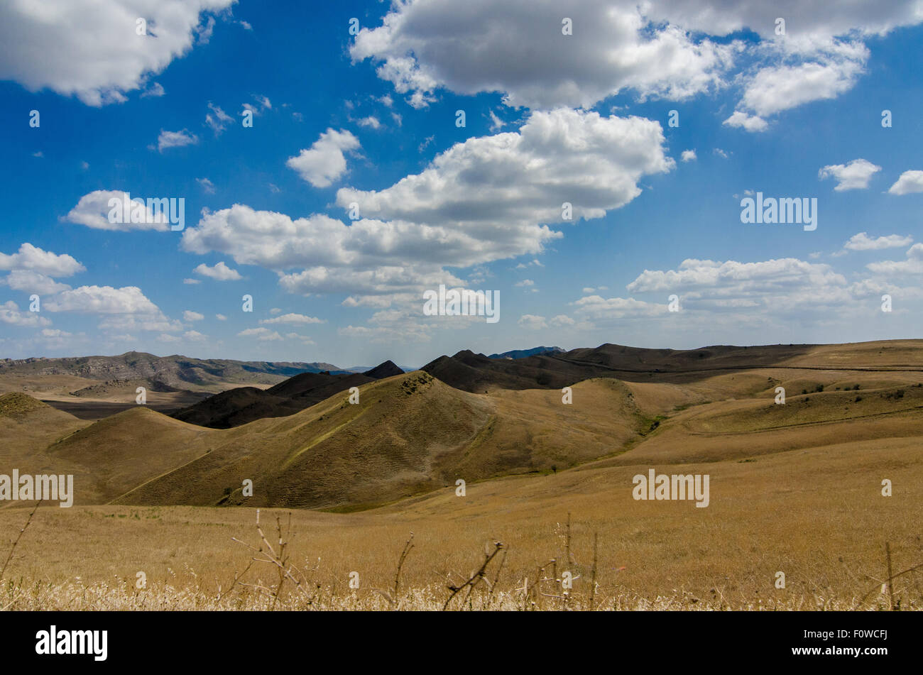 Scenic view of rolling hills and clouds under a bright blue sky in a ...