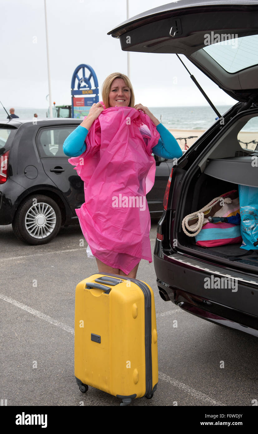 Female holidaymaker at a wet seaside resort unpacking her car. UK Stock Photo