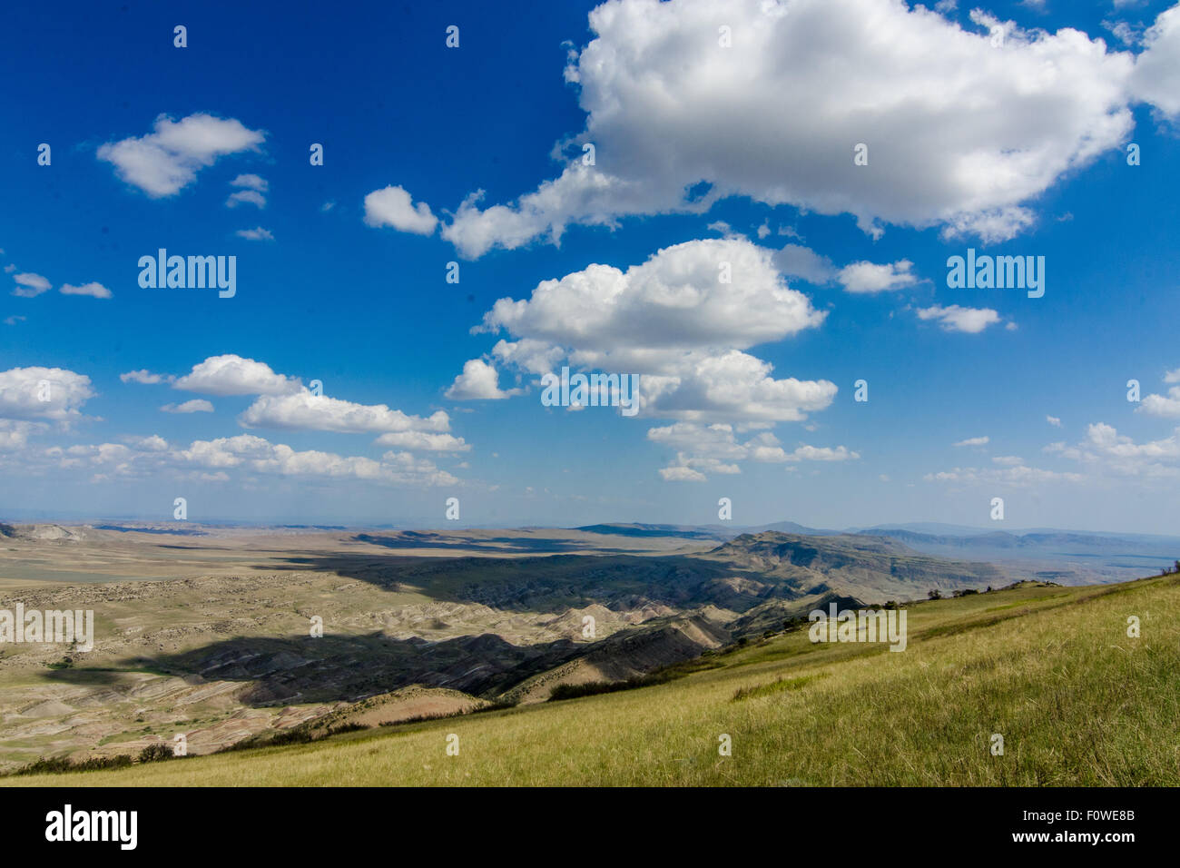 Scenic view of rolling hills and clouds under a bright blue sky in a ...