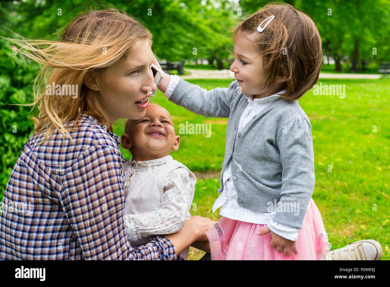 Cute toddler holding a smartphone to mother's ear Stock Photo