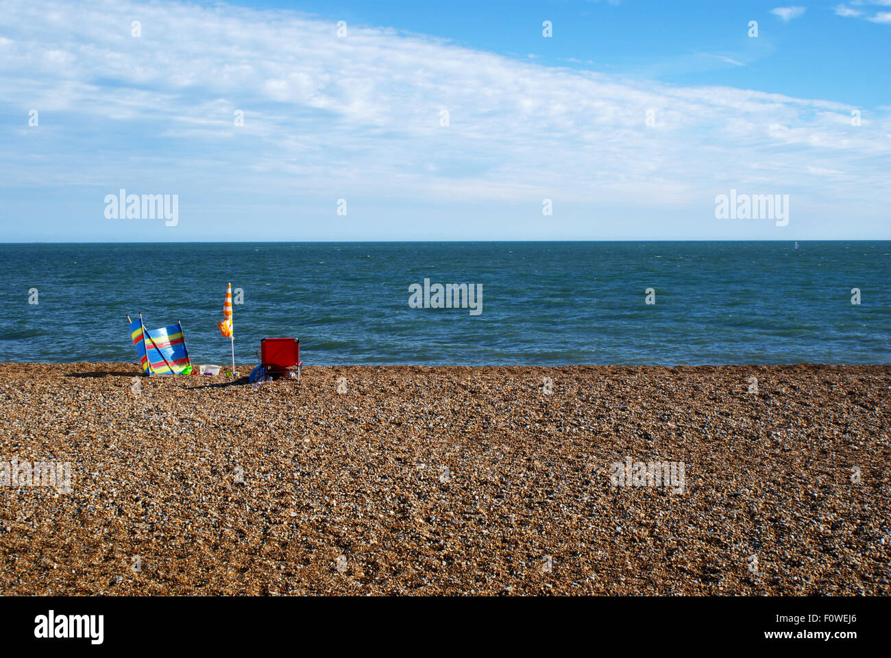 Colourful beach lounging set on stony beach facing calm sea, Hythe, Kent Stock Photo