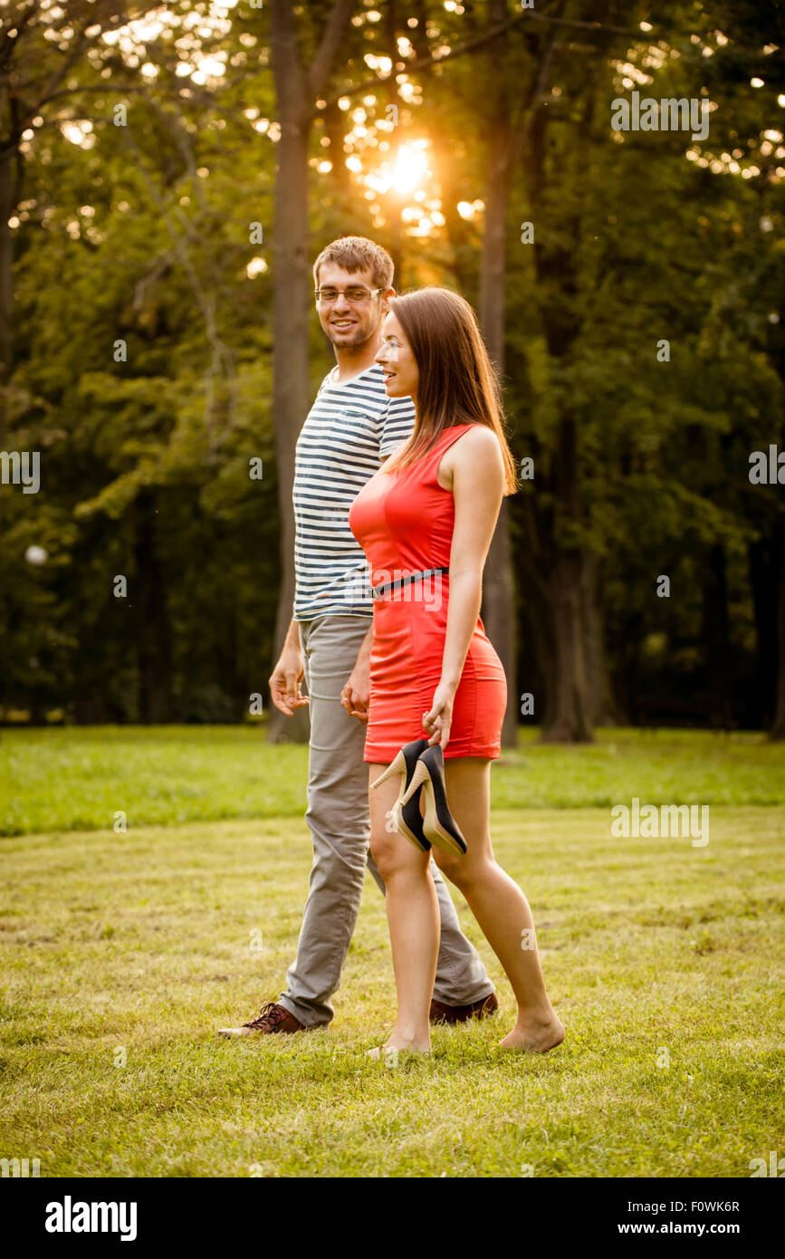 Couple walking in grass - woman is barefoot holding high heels shoes ...