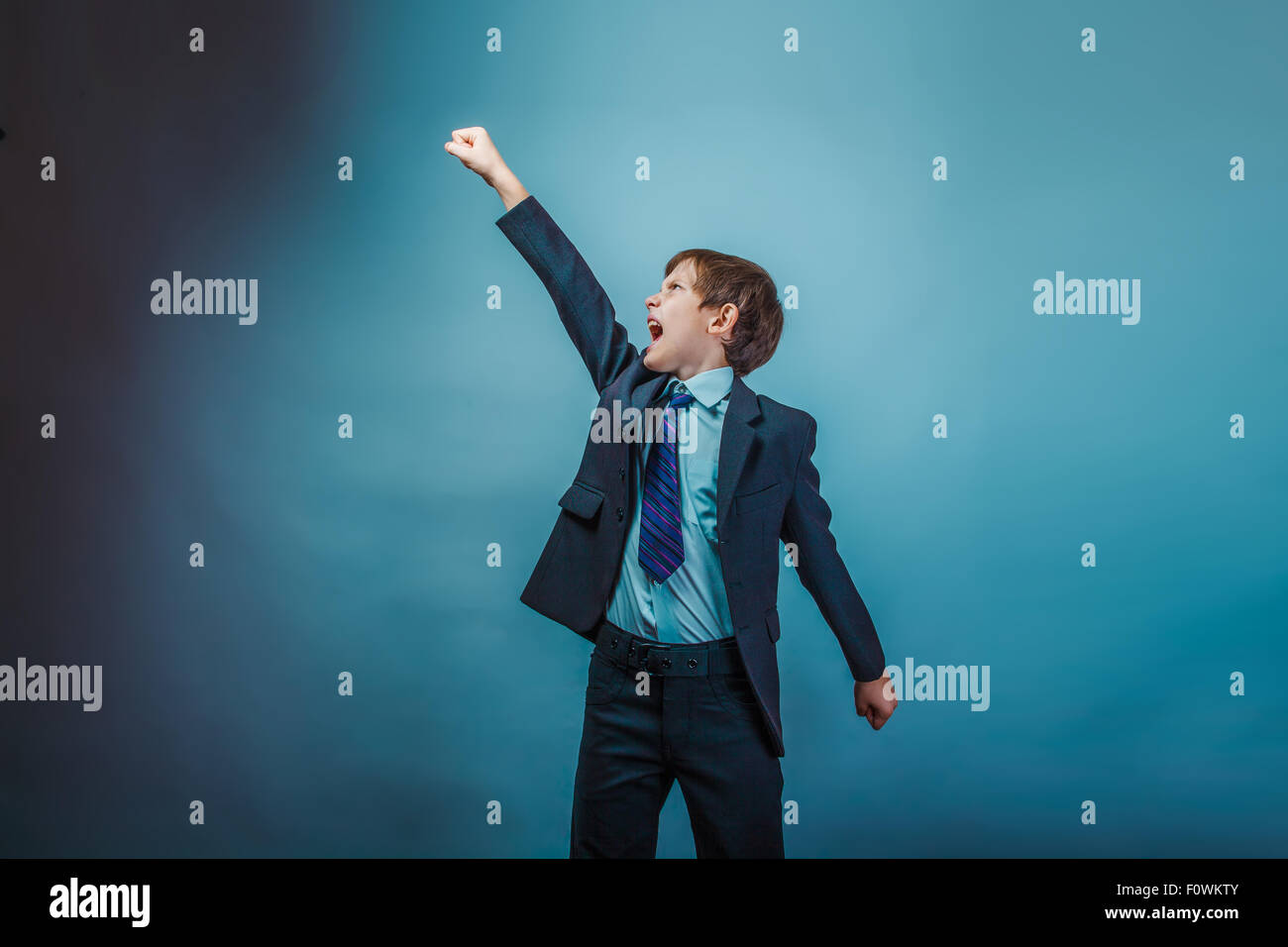 teenage boy superhero flying up raised his fist photo studio asp Stock Photo