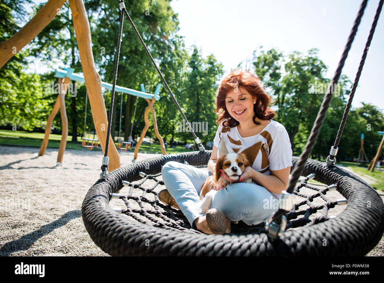 Mature woman swing with her cavalier dog outdoor in playground Stock Photo