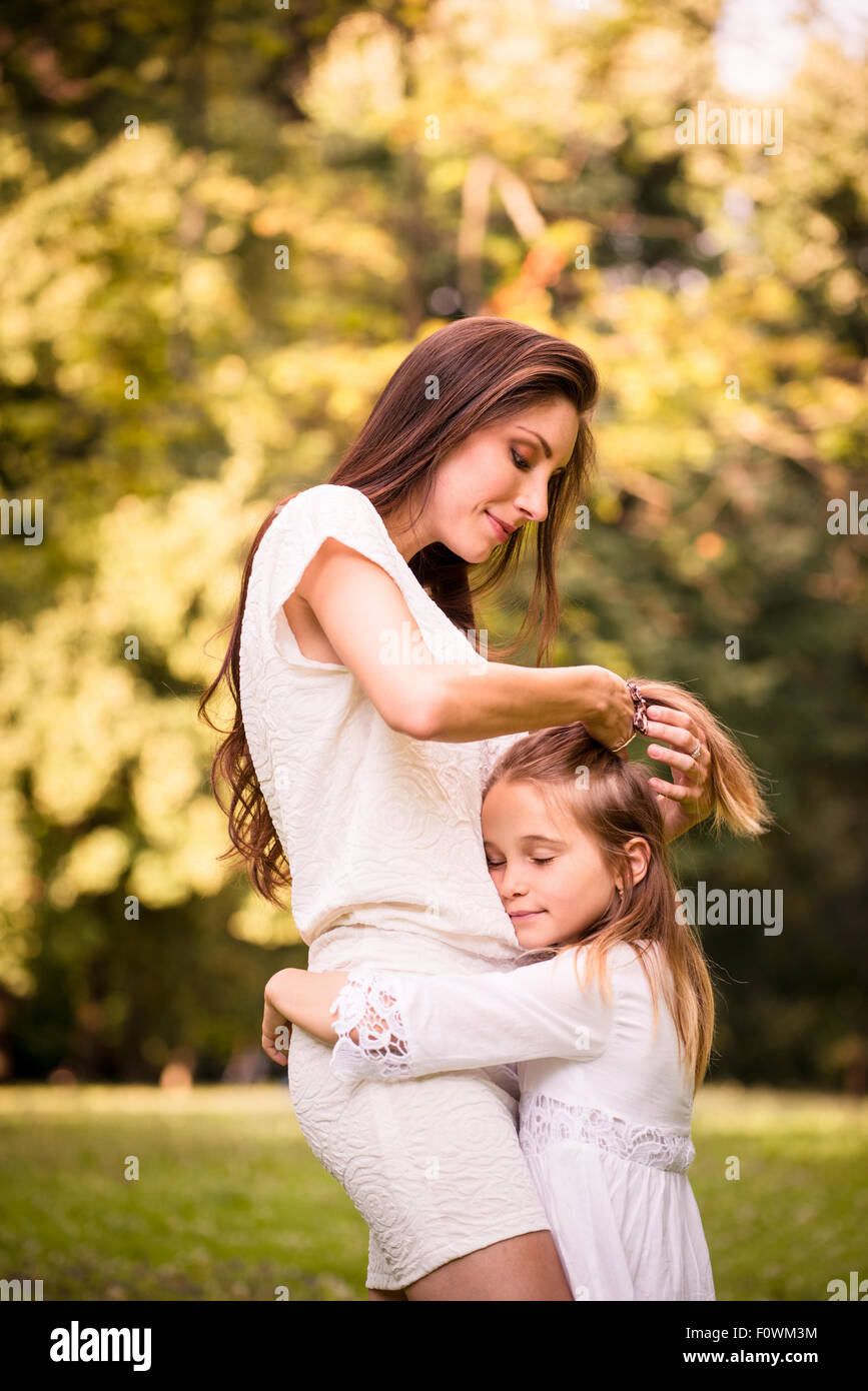 Mother is taking care of her daughter's hair - outdoor in nature Stock Photo