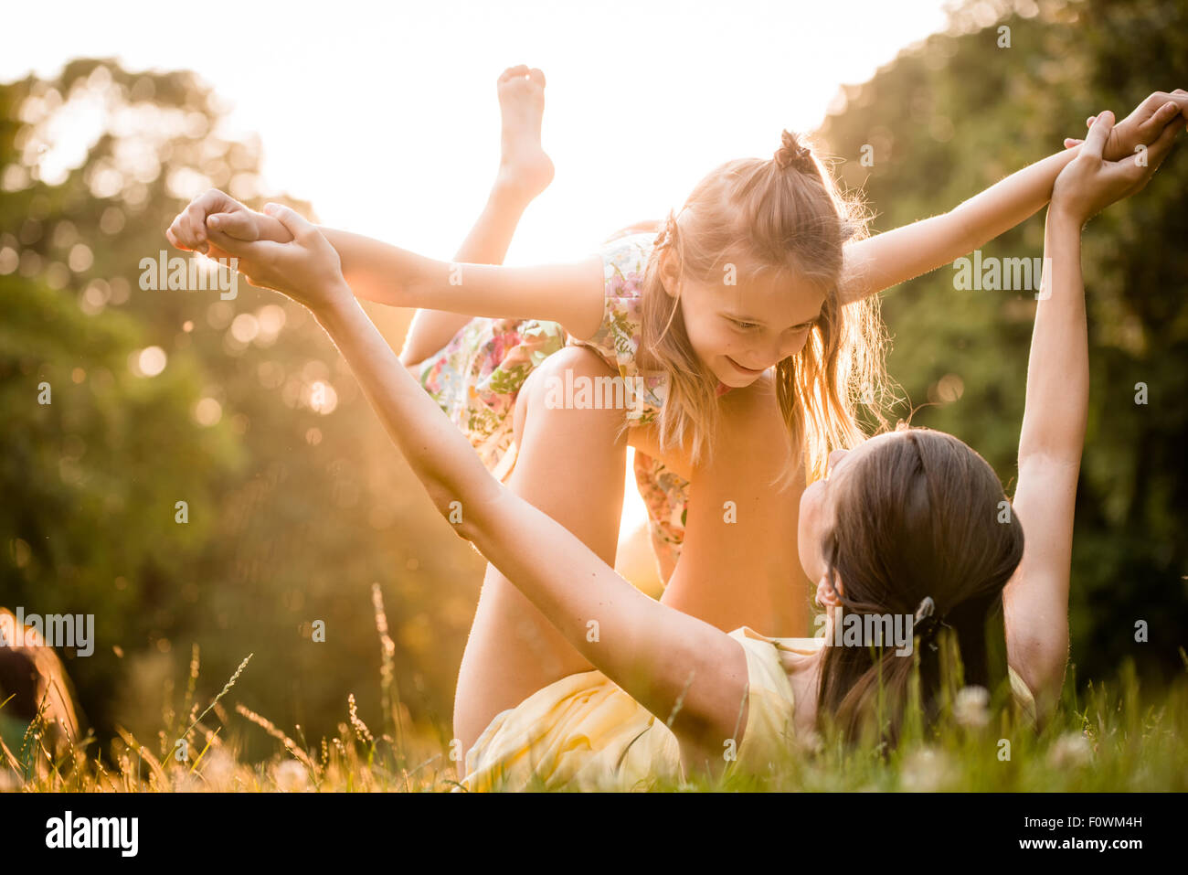 Mother lying down on grass and plays with her daughter on airplane Stock Photo