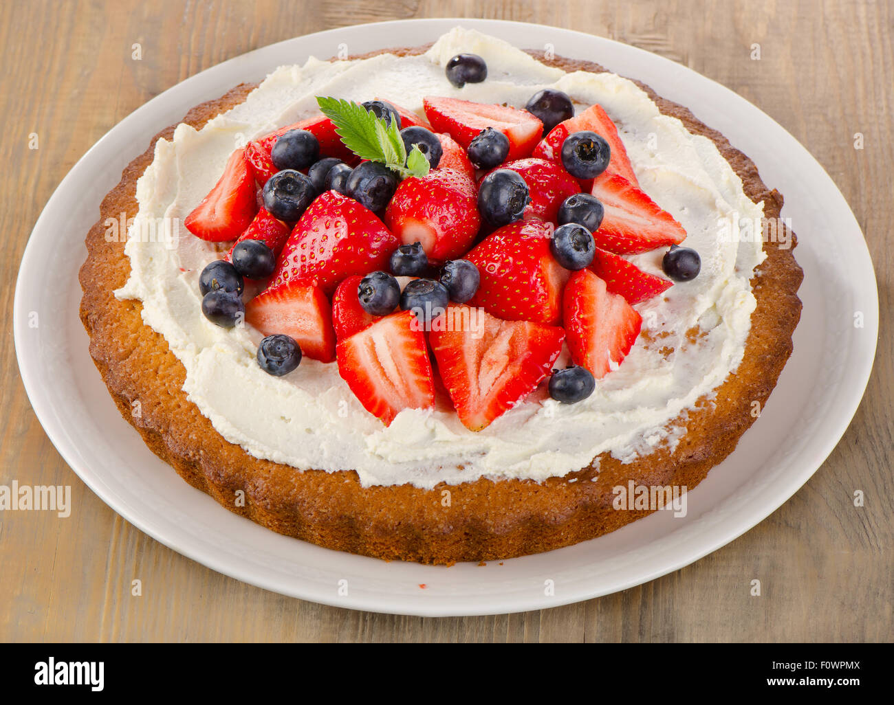 Strawberry and blueberry cream cake with mint. Closeup Stock Photo - Alamy