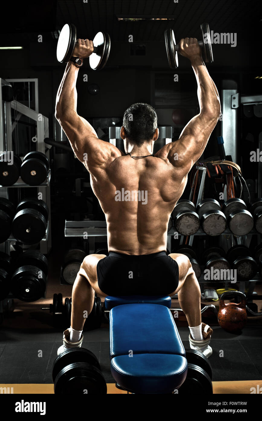 very brawny guy bodybuilder,  execute exercise with  dumbbells, on deltoid muscle shoulder Stock Photo