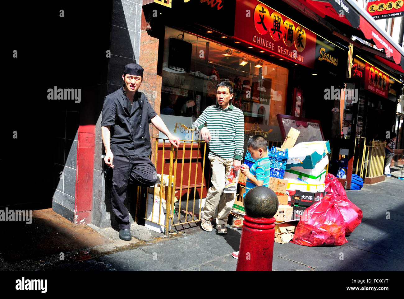 London, England, UK. Gerrard Street, Chinatown. Men talking and smoking outside a restaurant Stock Photo