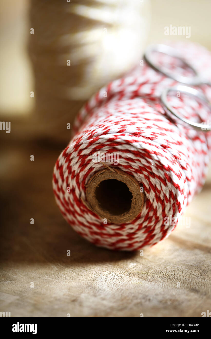 Spool of red and white twine with scissors on wooden background Stock Photo