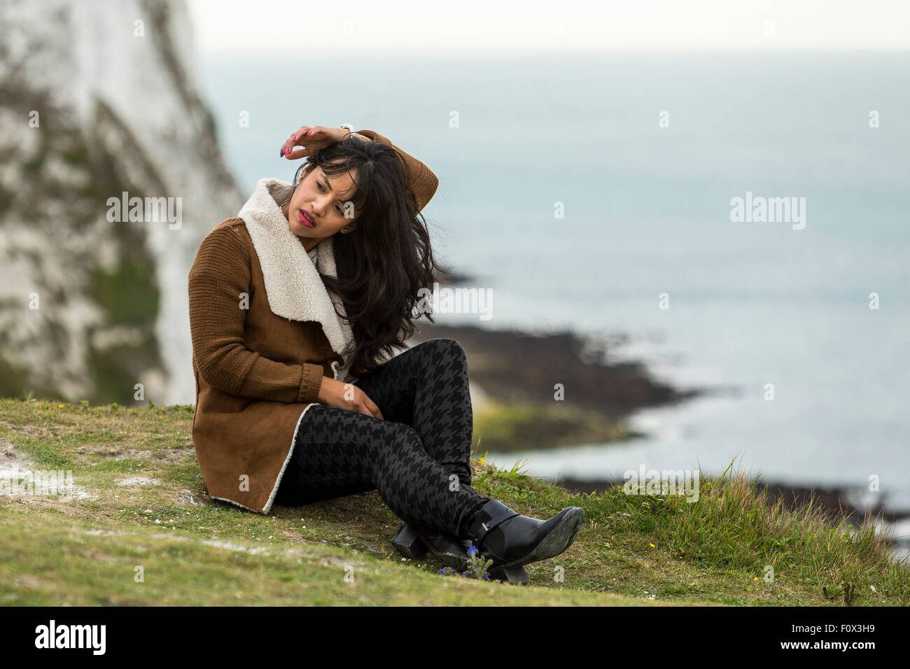 Young woman sitting on the grass. The White Cliffs of Dover, Dover, Kent, UK Stock Photo
