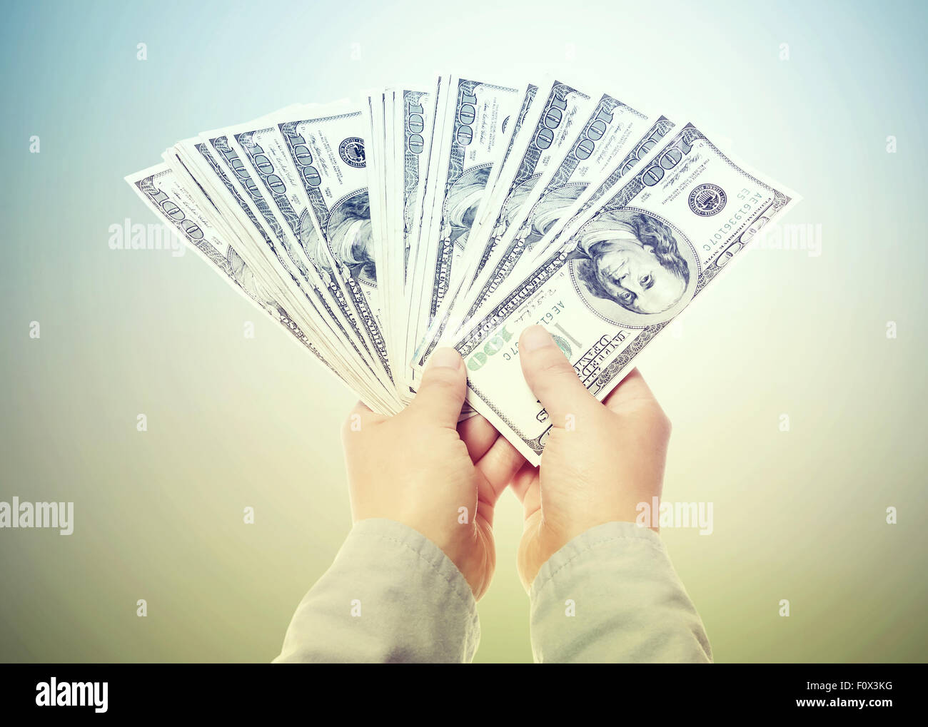 Hand Displaying a Spread of Cash in a Vintage Light Stock Photo