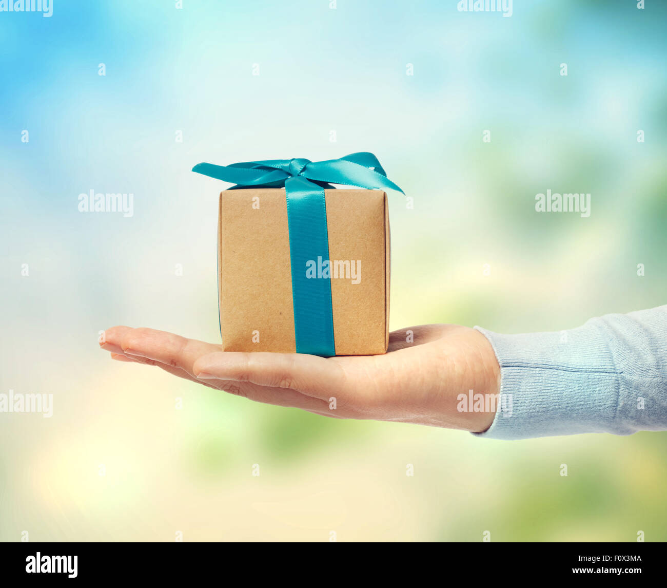 Small blue ribbon gift box on a hand Stock Photo