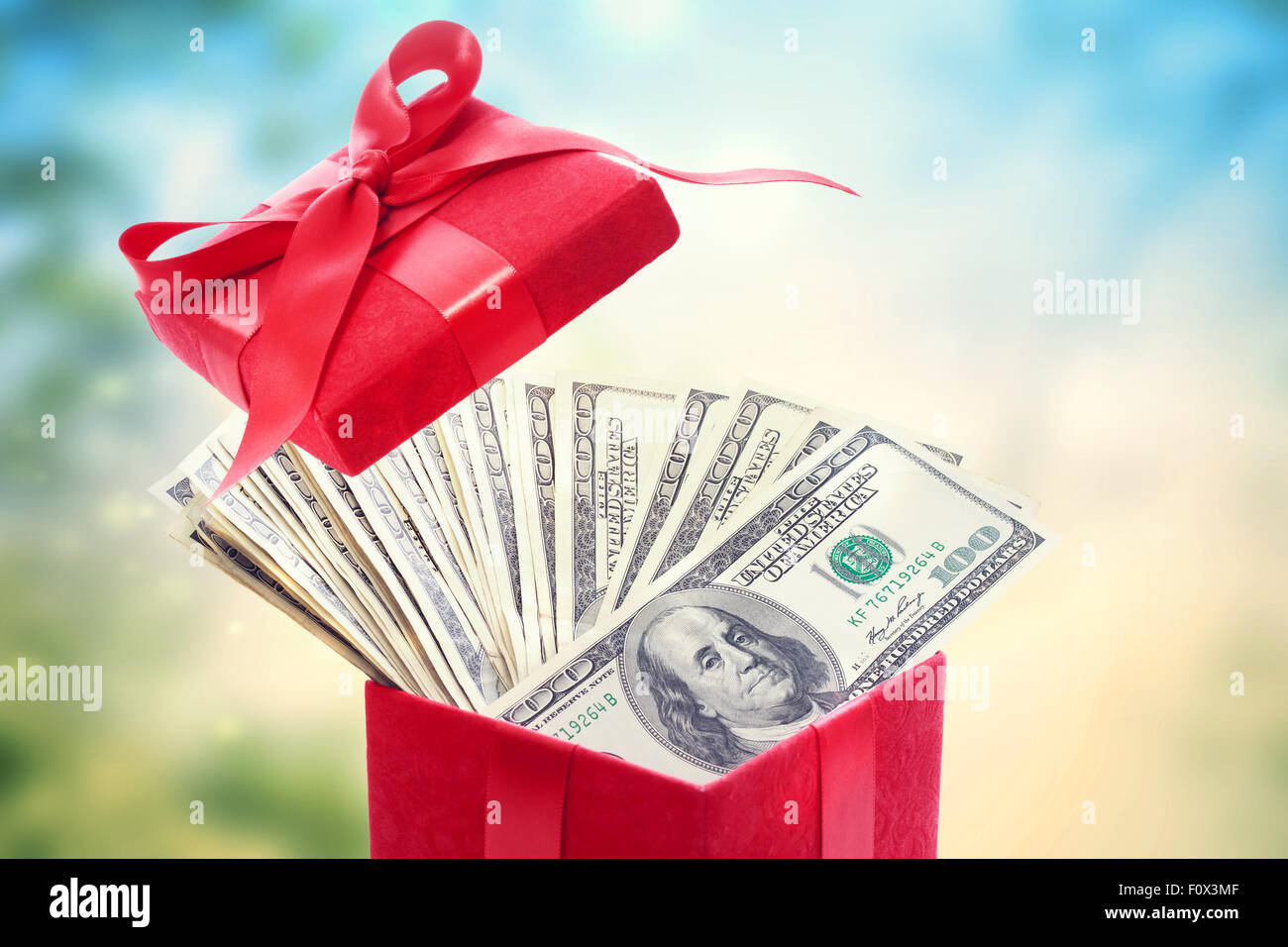 Heap of hundred dollar bills in a big red present box Stock Photo