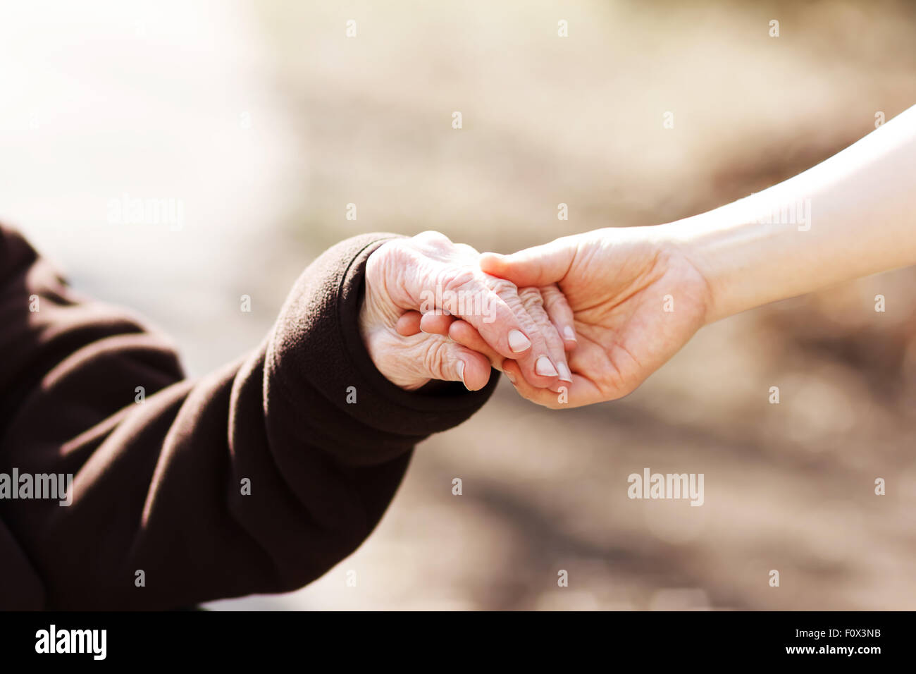 Elderly woman holding hands with young caretaker Stock Photo