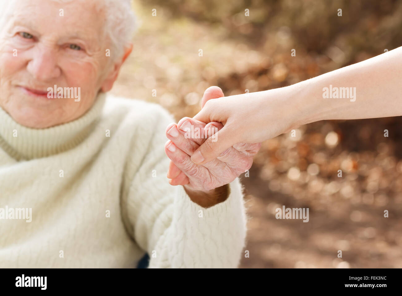 Elderly woman holding hands with young woman outside Stock Photo