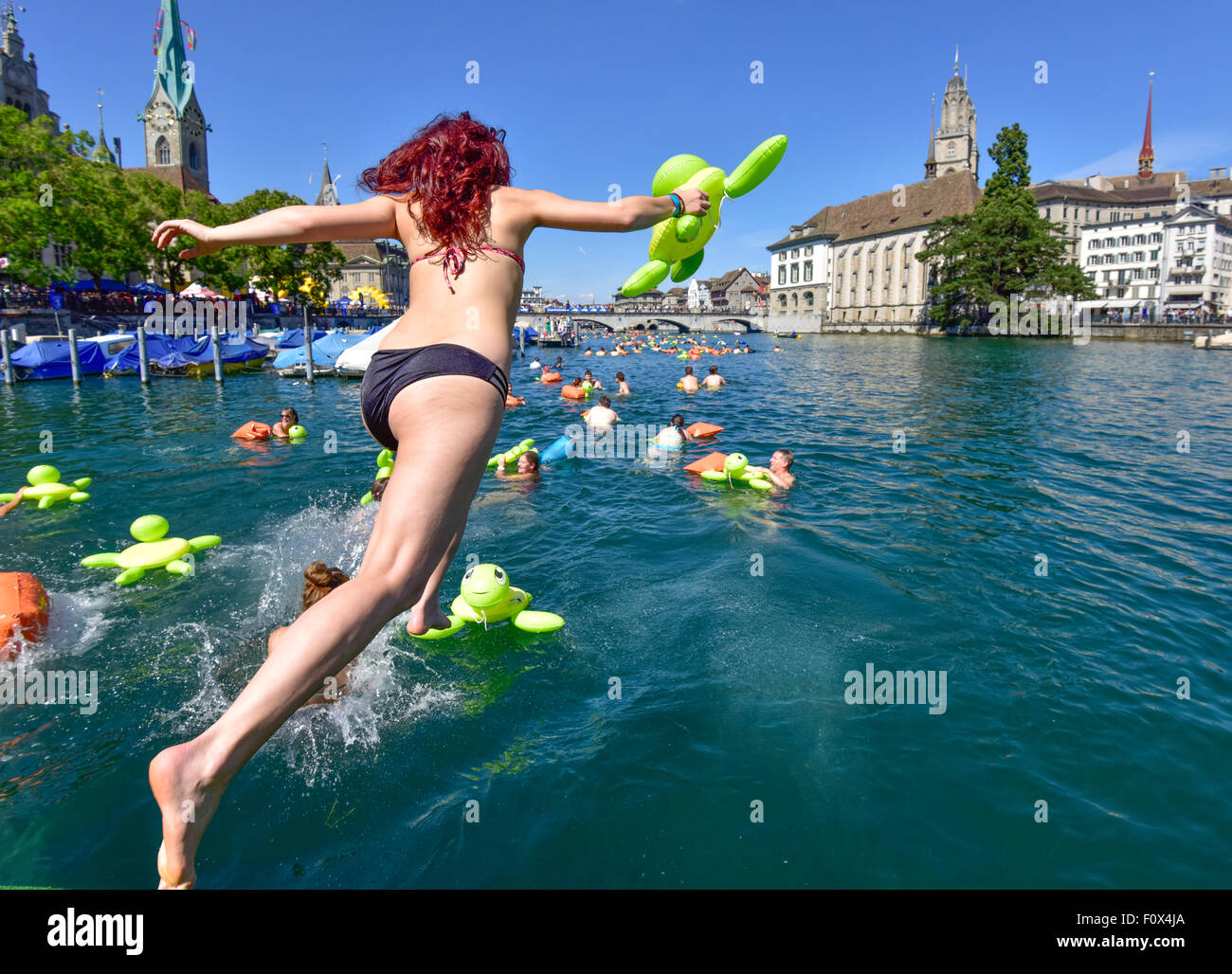 Zurich, Switzerland. 22nd August, 2015. A young woman is jumping into Zurich's cool Limmat river to drift down 2km through the city. Sunny weather and warm temperatures at Zurich's traditional 'Limmatschwimmen' ('swim down the Limmat river') attracted 4500 swimmers who, equipped with rubber turtles and other fancy floating devices, enjoyed drifting down the river through Zurich. Credit:  Erik Tham/Alamy Live News Stock Photo