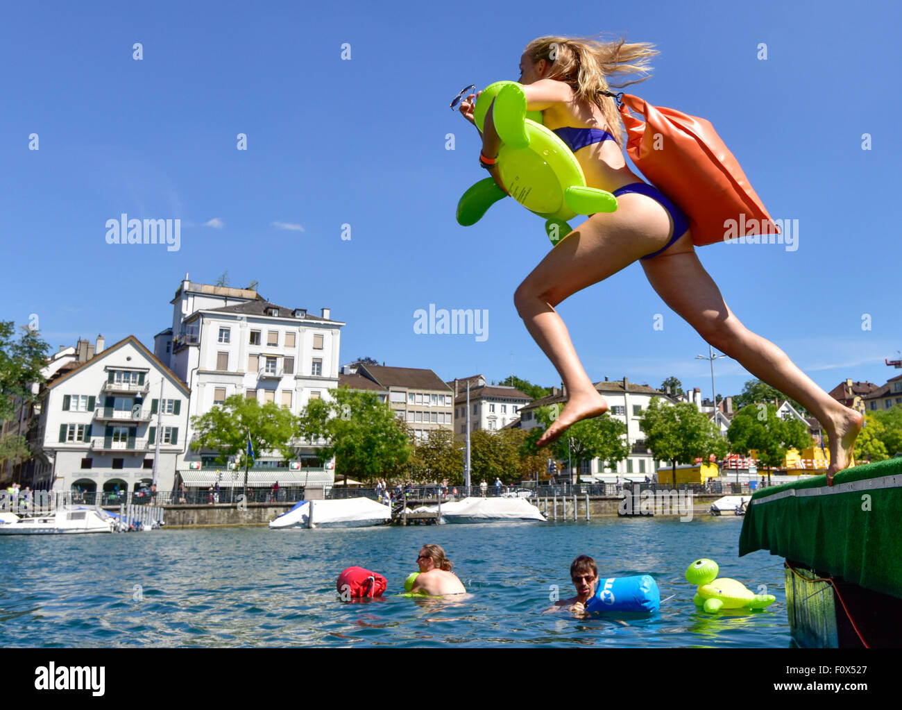 Zurich, Switzerland. 22nd August, 2015. A young woman is jumping into Zurich's cool Limmat river to drift down 2km through the city. Sunny weather and warm temperatures at Zurich's traditional 'Limmatschwimmen' ('swim down the Limmat river') attracted 4500 swimmers who, equipped with rubber turtles and other fancy floating devices, enjoyed drifting down the river through Zurich. Credit:  Erik Tham/Alamy Live News Stock Photo