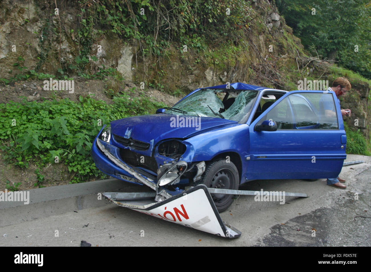 Blue car crash on road, accident as stone bolder went through windscreen, driver escaped unhurt. Stock Photo