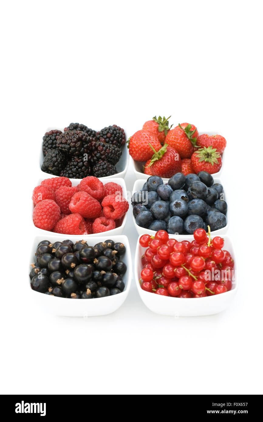 Redcurrants, Blackcurrants, Blackberries, Strawberries, Raspberries and Blueberries in white bowls on a white background. Stock Photo