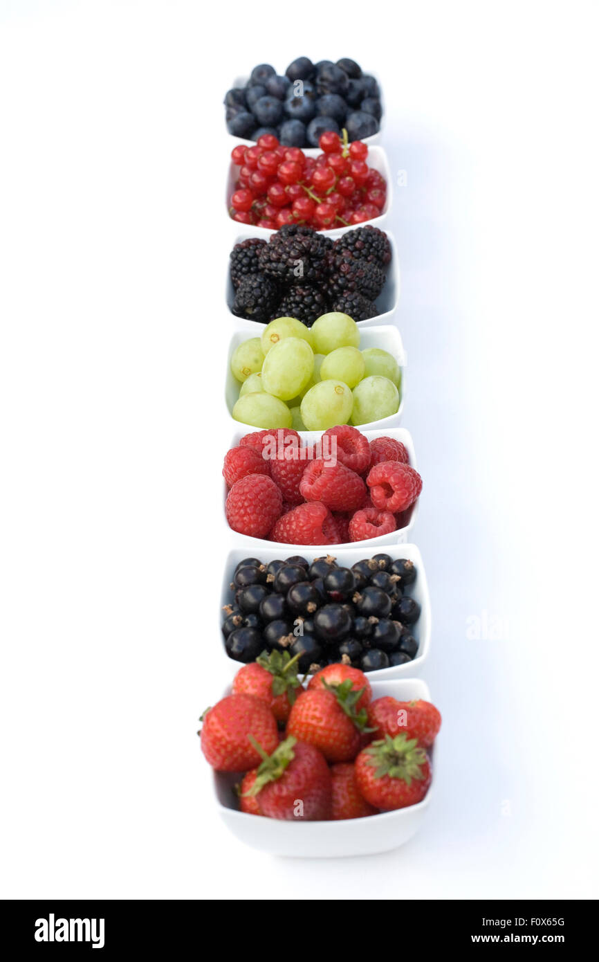 Redcurrants, Blackcurrants, Blackberries, Grapes, Strawberries, Raspberries and Blueberries in white bowls on a white background. Stock Photo