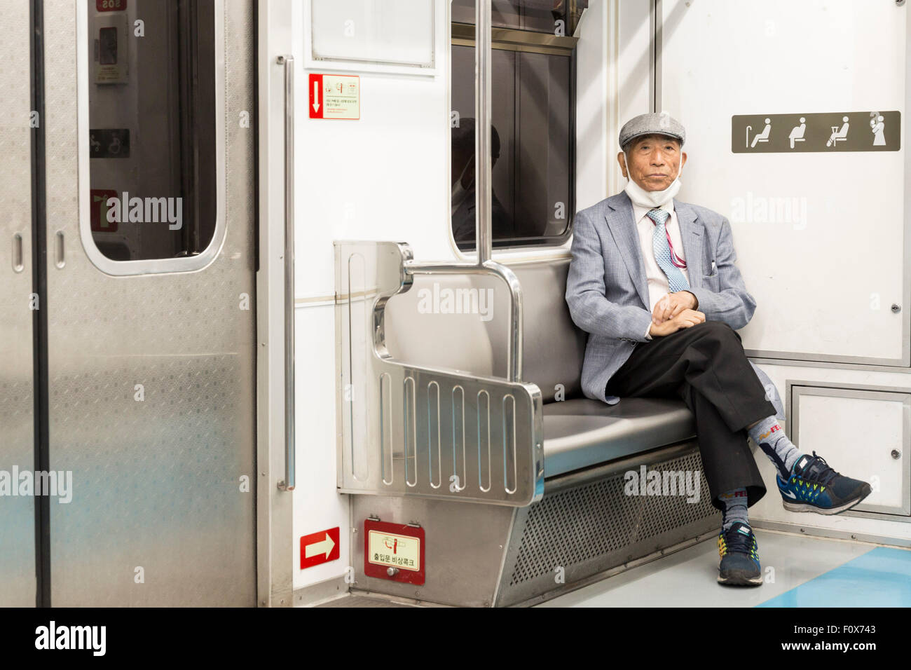 Man wearing mask sitting on a chair in Seoul's underground Stock Photo
