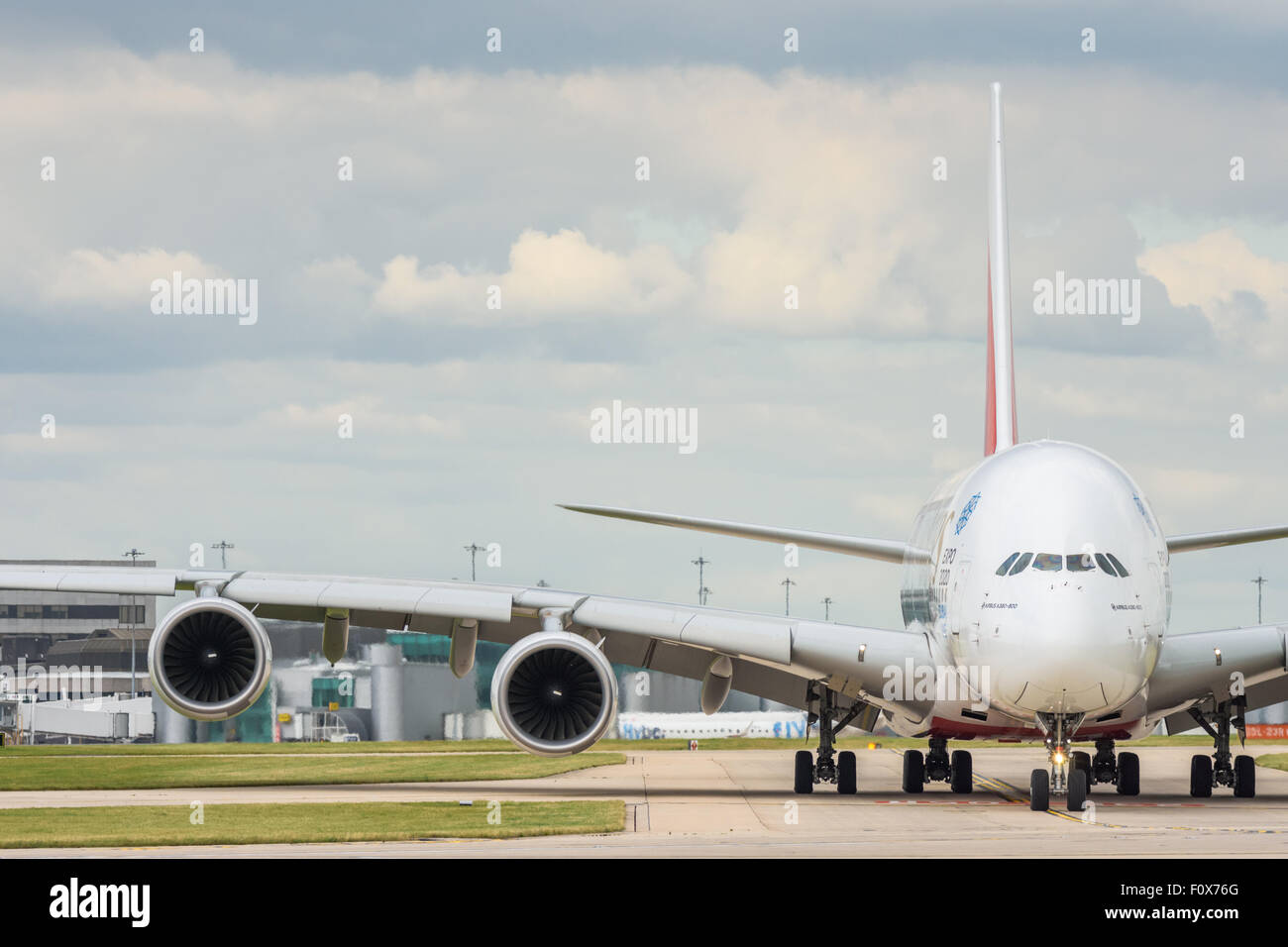 Head on view of an Emirates Airbus A380-800 aeroplane waiting to join the runway at Manchester Airport showing the massive wingspan of the aircraft Stock Photo