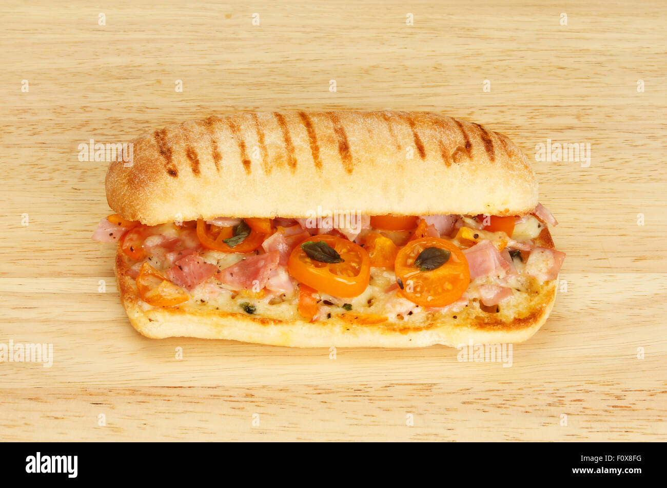 Ham,tomato,cheese and basil panini on a wooden board Stock Photo