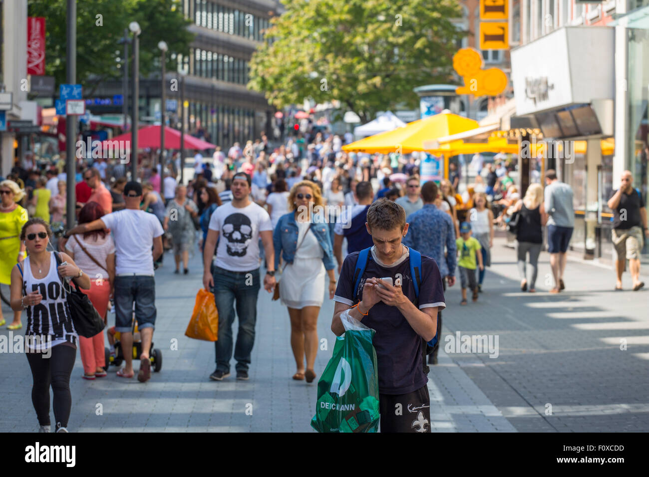 Main shopping street in the city center of Aachen with a man attending his smart phone Stock Photo