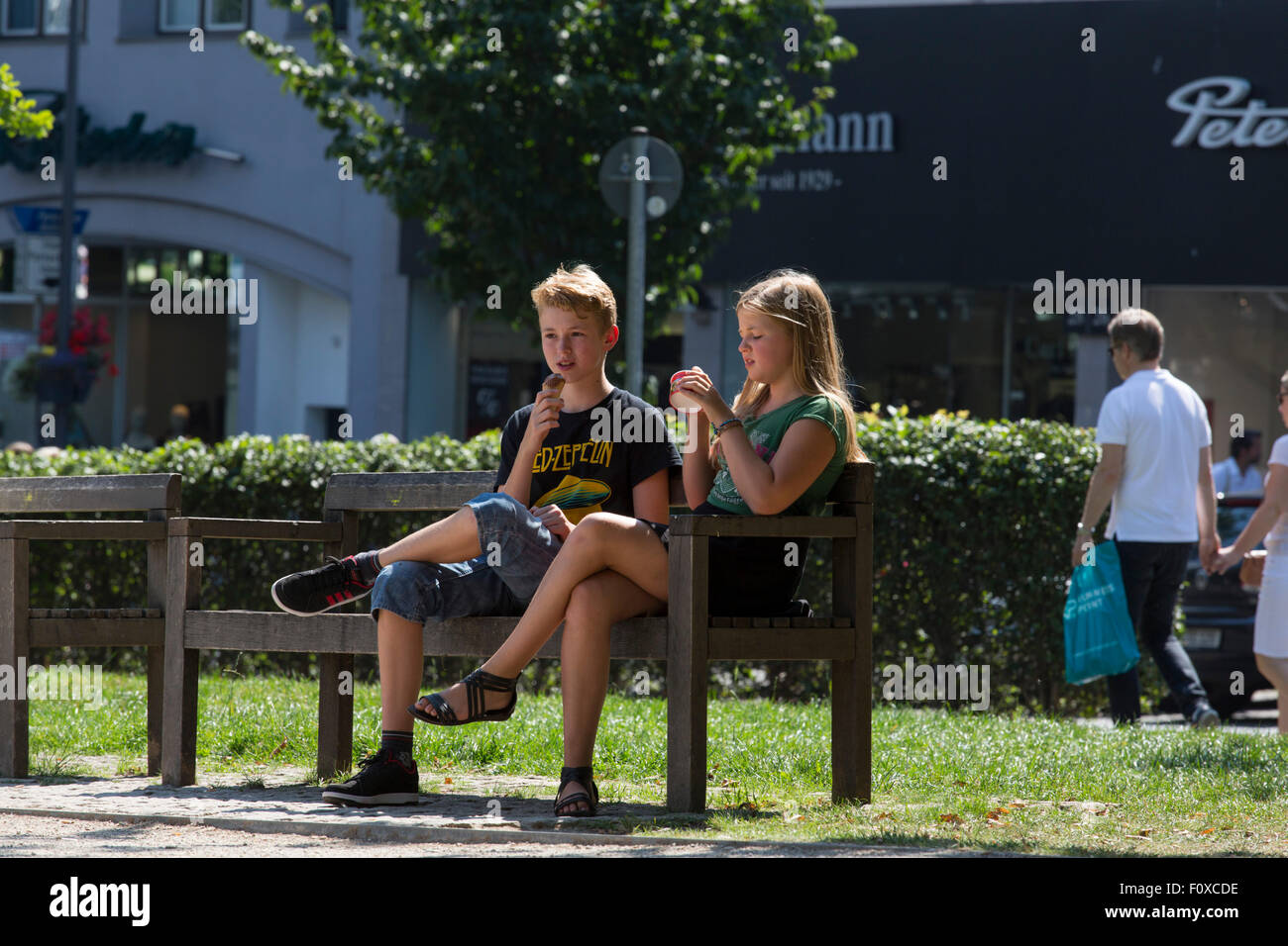 A boy and a girl eating ice cream on a warm summer day in the park of Aachen in Germany Stock Photo