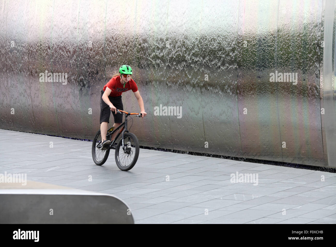 Stunt cyclist in front of the Cutting Edge steel sculpture at Sheffield Railway station Stock Photo