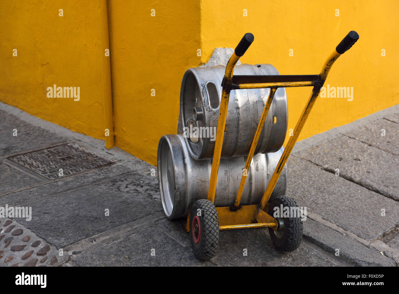 Yellow wall and dolly holding beer canisters in street of Cordoba Spain Stock Photo