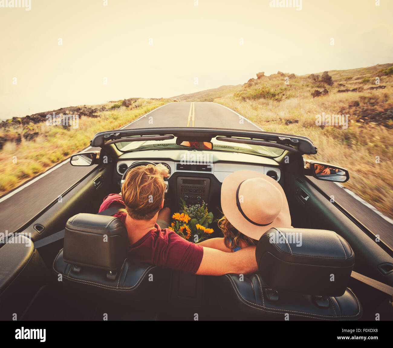 Happy Young Couple Driving Along Country Road in Convertible at Sunset ...