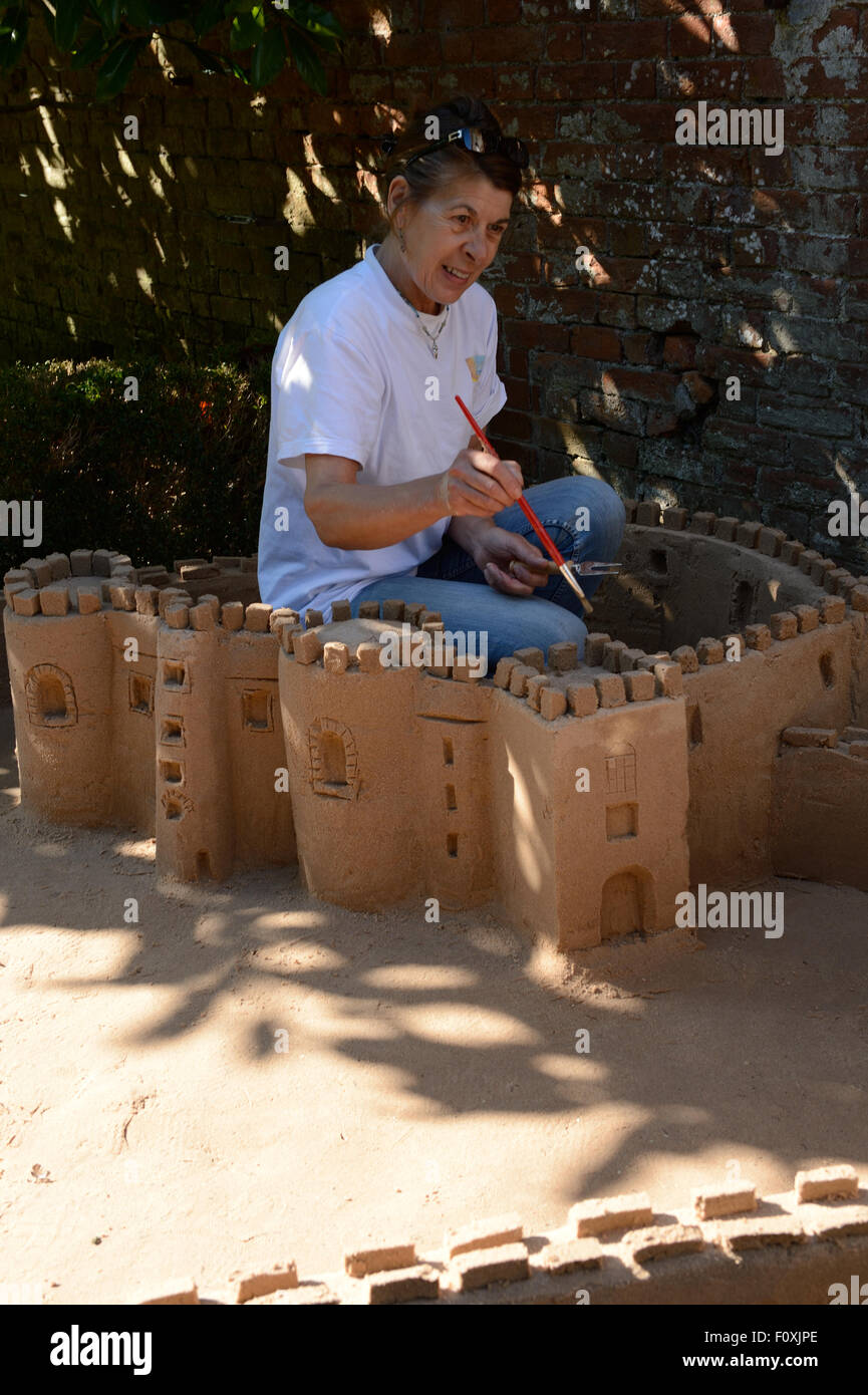 sand castle building at Laugharne castle using a paintbrush for finishing touches Stock Photo