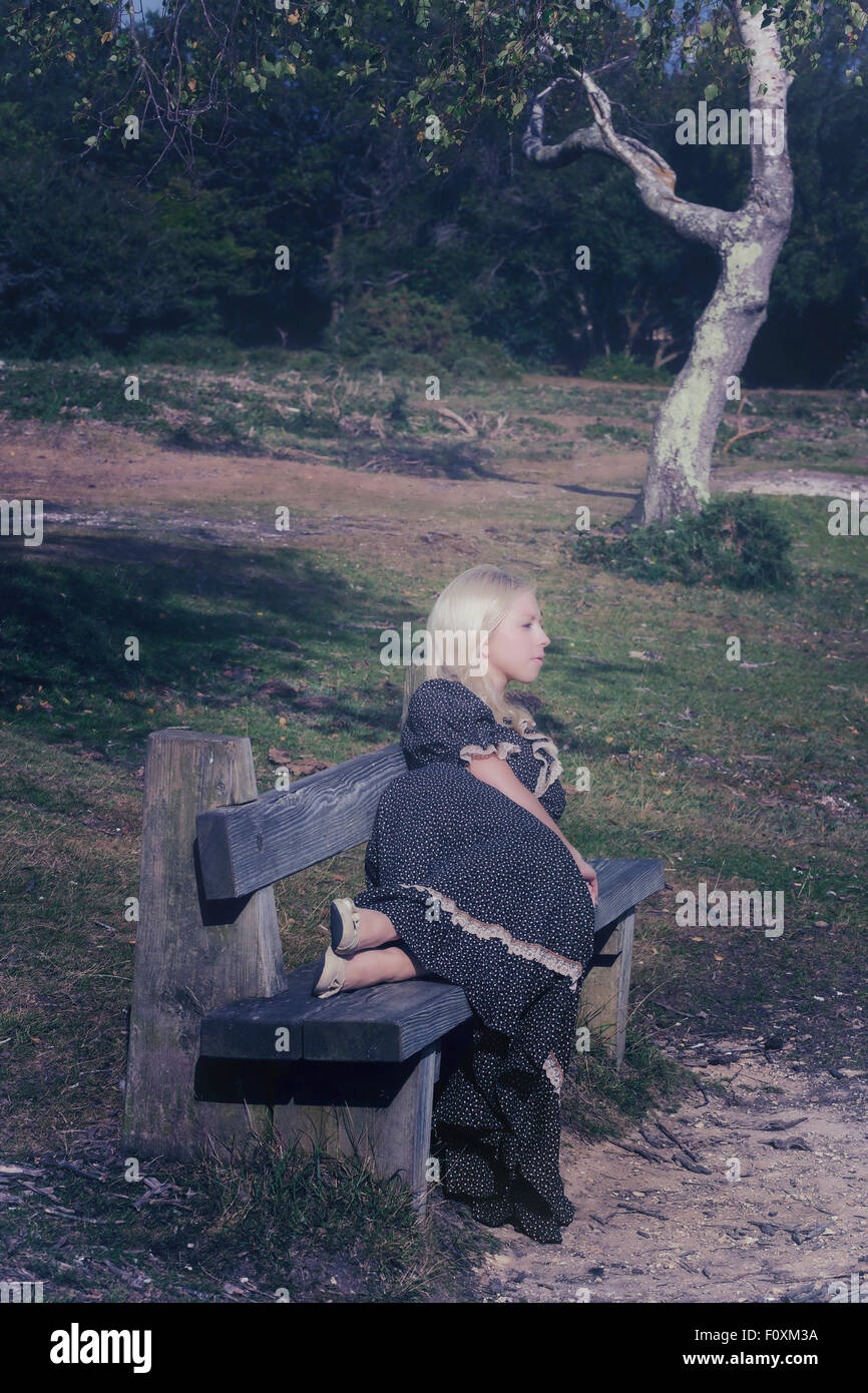 a blond girl is lying on a bench Stock Photo