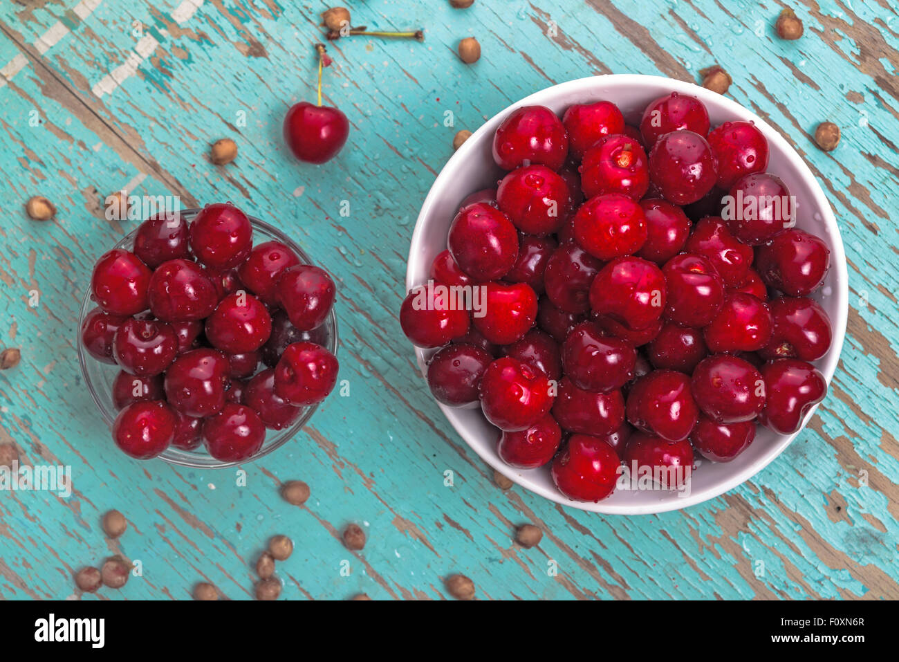 Sweet Cherry in Bowl on Rustic Table, Ripe Fresh Wild Cherries Fruit and Cherry Pits, top view Stock Photo