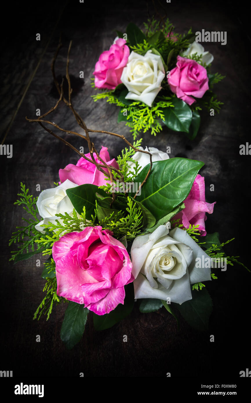 still life decorated pink and white roses with various leaves on dark wooden background Stock Photo