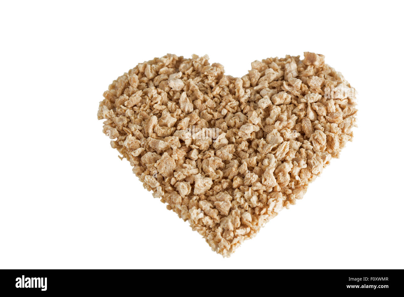 Heart shape made of textured soy protein granules, tilted angle, isolated on white background. Stock Photo